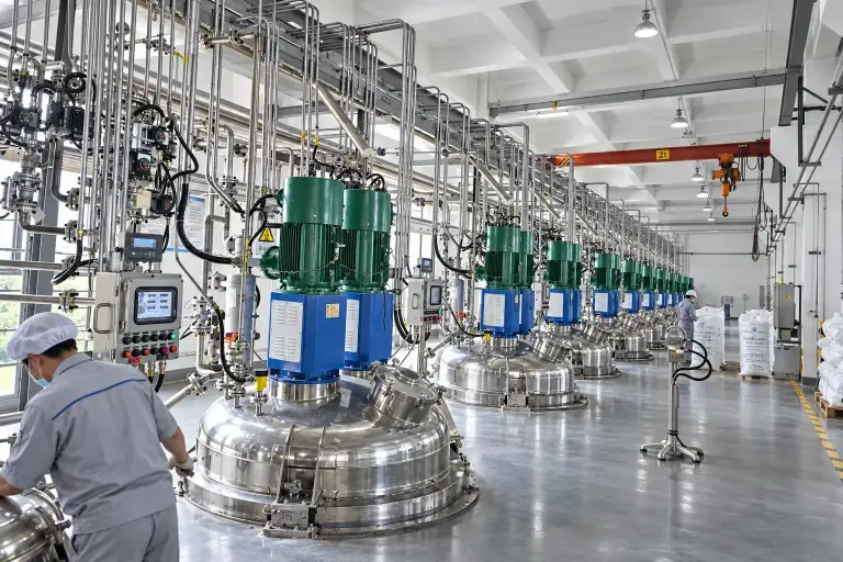 Operator at the control panel of a row of heated mixing vessels, each with a direct-drive agitator motor