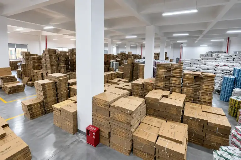 Packaging store with flat-packed cartons and bagged materials stacked by type along marked aisles