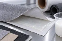 Fabric, foam and film layers laminated together, with a tub of dispersion and a coating blade